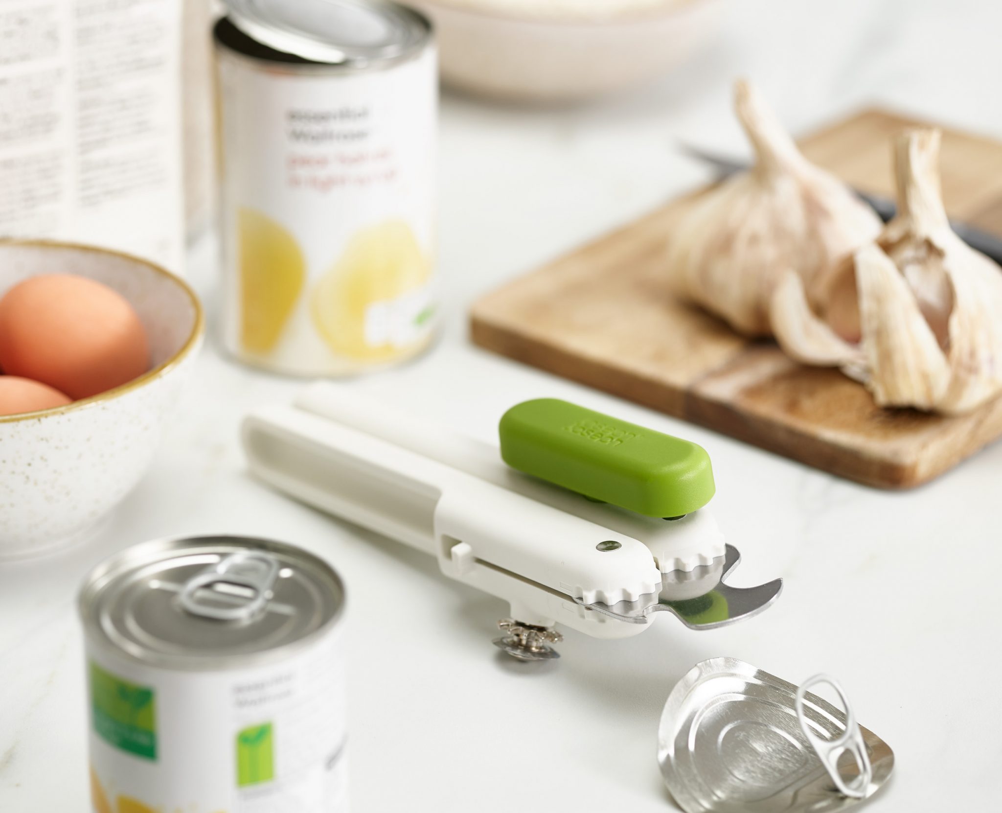 Joseph Joseph 3-in-1 Can Opener in white/green beside open cans